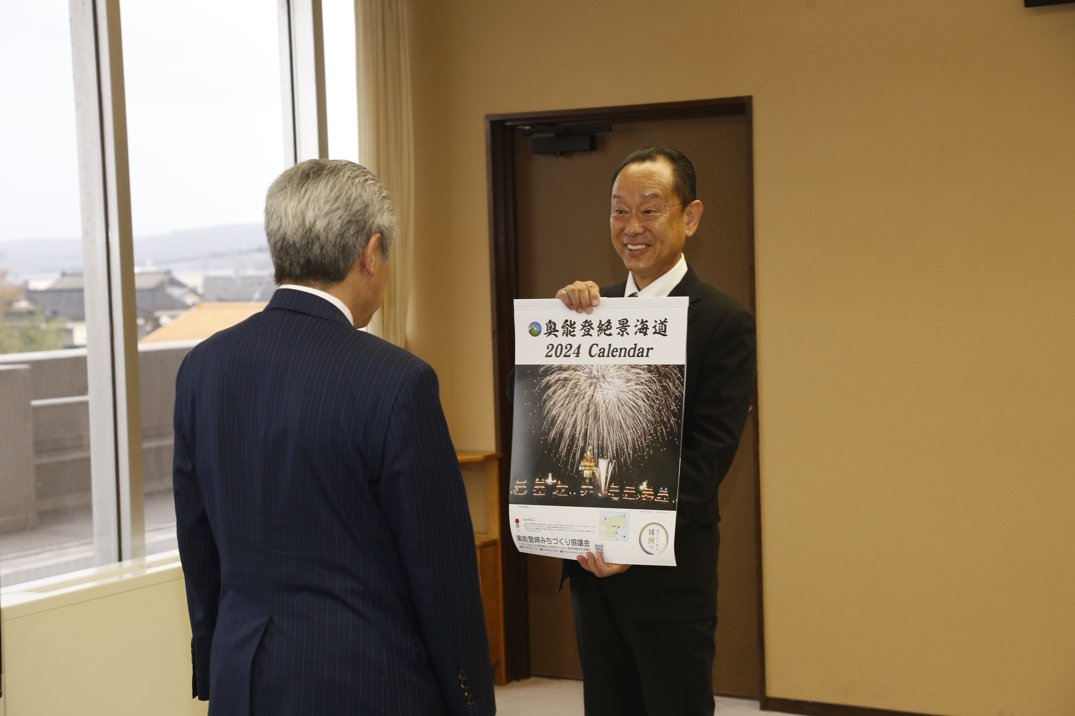 カレンダーを披露する刀祢会長の画像